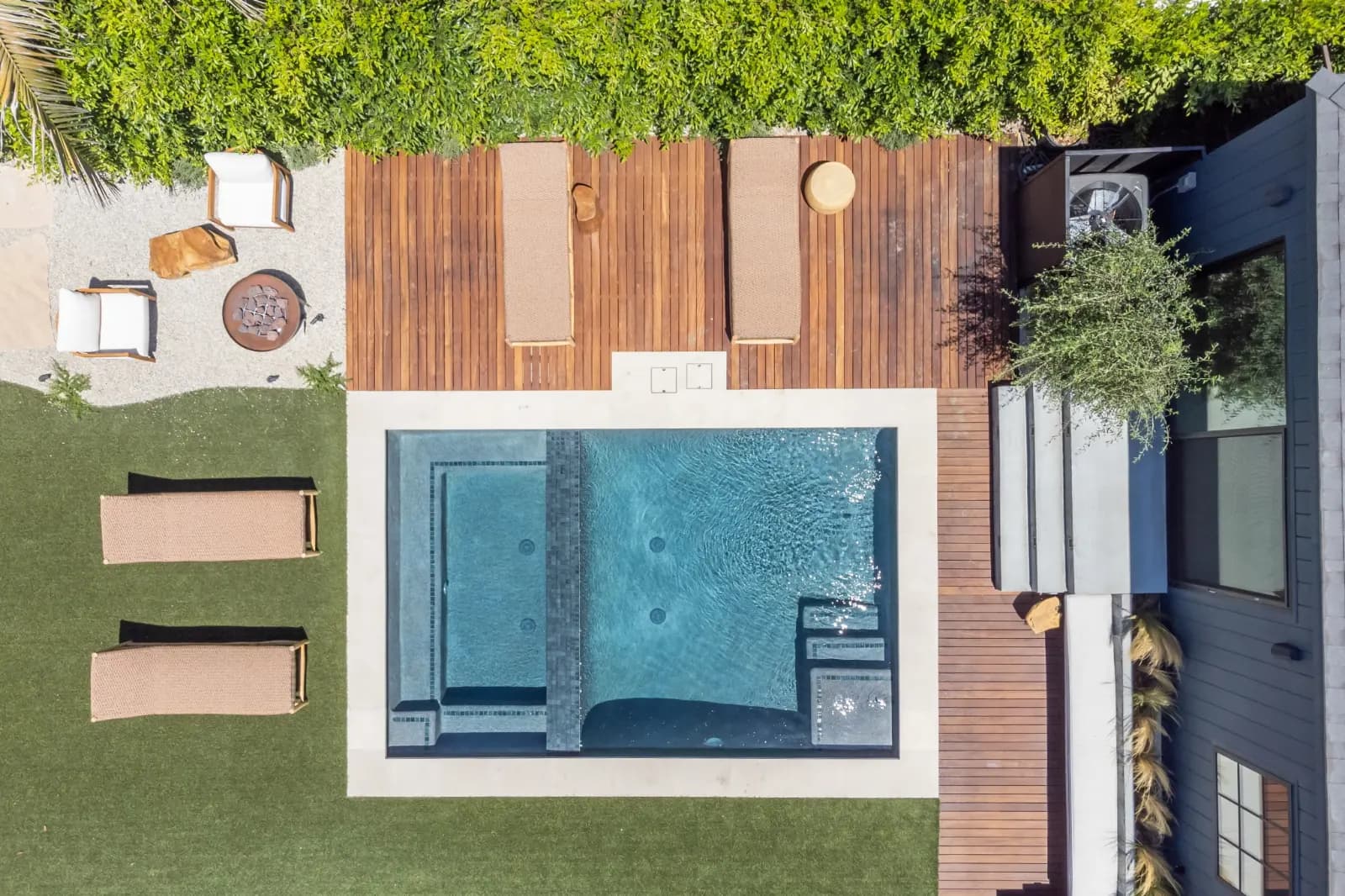 Overhead view of a rectangular backyard pool with a wood deck, paving and a lawn.