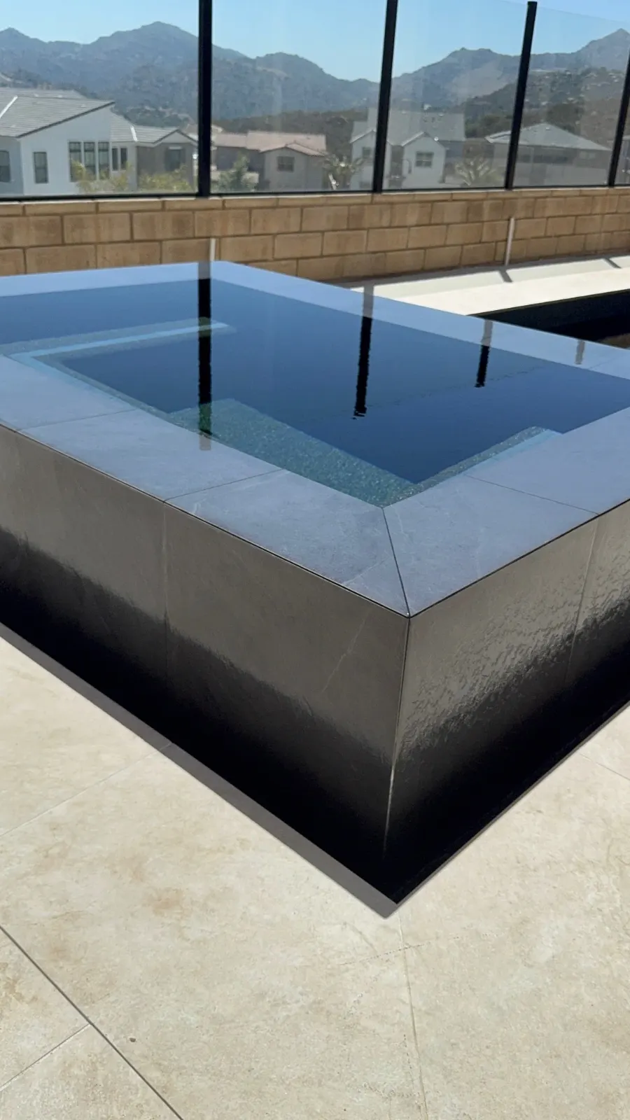 Close view of a spa corner showing dark waterline tile and the coping edge above the water.