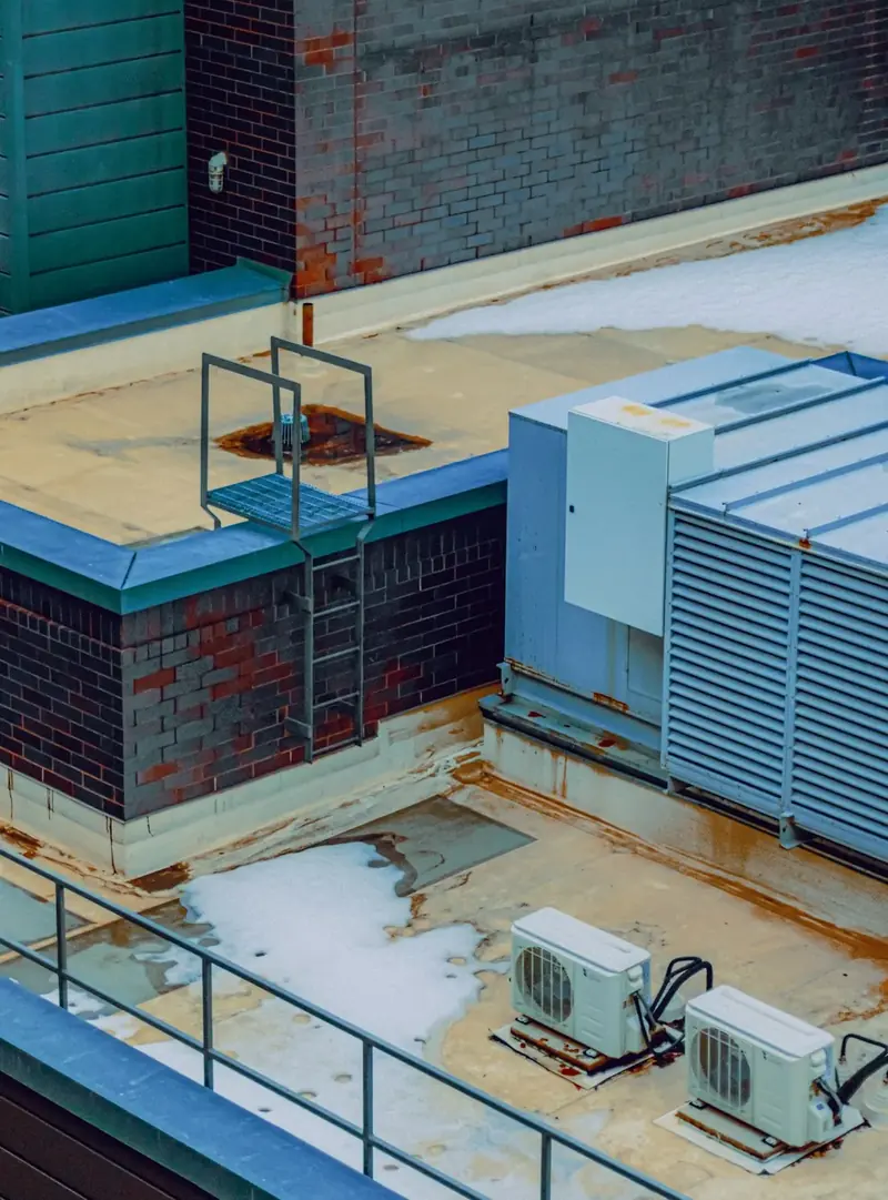 Rooftop mechanical area with HVAC units and a ladder, seen from above.